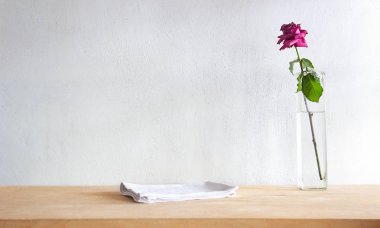 Beyaz masa çarşafları ve kırmızı ile rustik masa, grunge çimento duvara karşı kuru gül. Vintage arka plan şablonu, ürün ekran montaj.