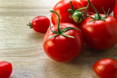 Tahta bir arka planda, küçük bir şeyle çevrili bir avuç dolusu büyük domates.