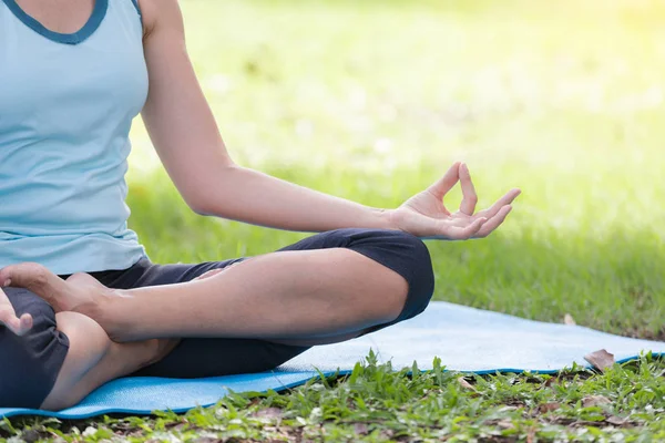Yoga yapan tatilci kadın, halk parkında meditasyon yapıyor. Spor Sağlıklı Konsept..