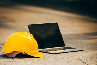 Closeup nesne sarı Emanet şapka ve arka bina ile zemin beton üstünde laptop