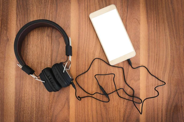 Akıllı telefon ve kulaklık için ahşap arka plan üzerinde müzik dinlemek