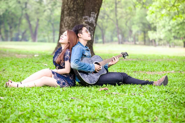 Asiatico Coppia Amore Giocare Acustica Canzone Chitarra Seduta Erba Parco — Foto Stock