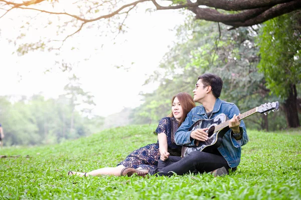 Asiatico Coppia Amore Giocare Acustica Canzone Chitarra Seduta Erba Parco — Foto Stock