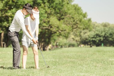 Asya çift golf oynuyor. adam dururken Golf sahasında oynamak için kadın öğretim