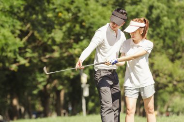 Asya çift golf oynuyor. adam dururken Golf sahasında oynamak için kadın öğretim