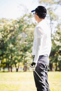 Asya adam golf oynuyor. Erkekler golf dururken sahada oynamak.