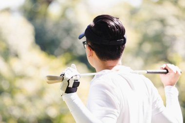 Asya adam golf oynuyor. Erkekler golf dururken sahada oynamak.