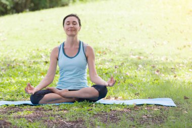 Yoga yapan tatilci kadın, halk parkında meditasyon yapıyor. Spor Sağlıklı Konsept..