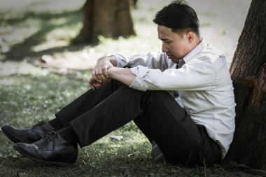 Asya iş adamı yetersiz kalıyor ve parkta ağaç altında ciddi