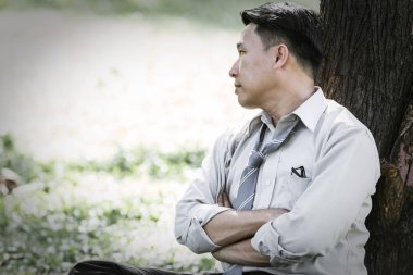 Asya iş adamı yetersiz kalıyor ve parkta ağaç altında ciddi