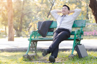 Yeşil ahşap sandalye gevşeme parkta oturmak portre Asya iş adamı