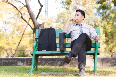 Yeşil ahşap sandalye gevşeme parkta oturmak portre Asya iş adamı