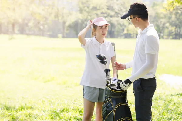 Asya çift golf oynuyor. adam dururken Golf sahasında oynamak için kadın öğretim