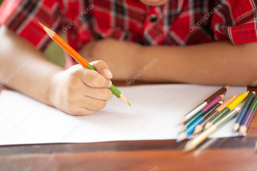 Asian little boy use color pencil writing on white paper