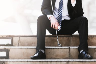 Golf kulüpleri iş adamları tutun ve golf topları şehirde üzgün oturmak.