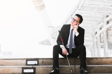 Golf kulüpleri iş adamları tutun ve golf topları şehirde üzgün oturmak.