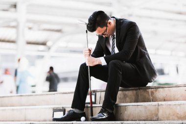 Golf kulüpleri iş adamları tutun ve golf topları şehirde üzgün oturmak.