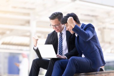 Asyalı iki işadamları oturan şehir içinde laptop üzerinde çalışıyoruz