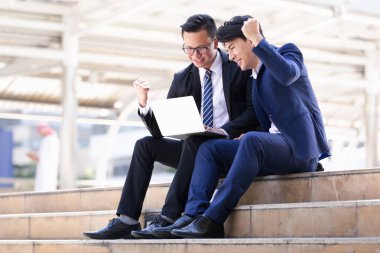 Asyalı iki işadamları oturan şehir içinde laptop üzerinde çalışıyoruz
