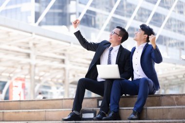 Asyalı iki işadamları oturan şehir içinde laptop üzerinde çalışıyoruz