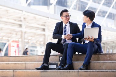 Asyalı iki işadamları oturan şehir içinde laptop üzerinde çalışıyoruz