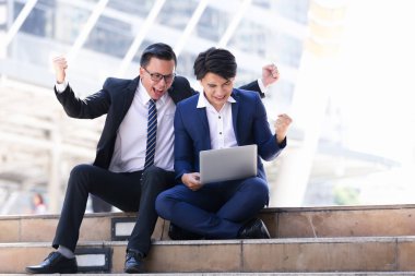 Asyalı iki işadamları oturan şehir içinde laptop üzerinde çalışıyoruz