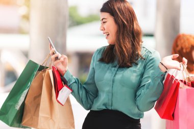 Güzel kızlar alışveriş online oynarken bir akıllı telefon kullanarak şehirde alışveriş torbaları, holding