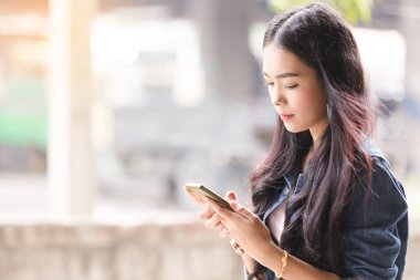 Asya portre genç kız kot pantolon smartphone kullanarak
