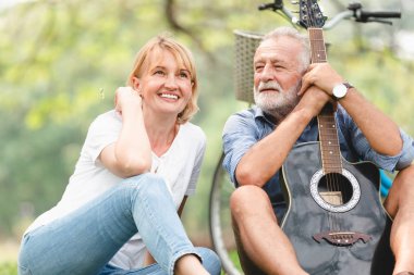 Üst düzey çift çimen parkta oturan akustik şarkı gitar çalmak aşık