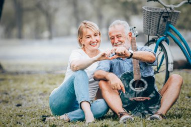 Üst düzey iki aşk içinde el yapımı kalp çim parkta oturan simge şeklinde göster