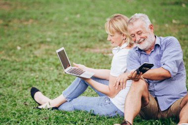 Üst düzey çift çimen parkta otururken müzik keyfini çıkarın