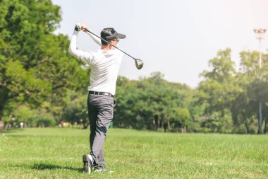 Asya adam golf oynuyor. Erkekler golf dururken sahada oynamak.