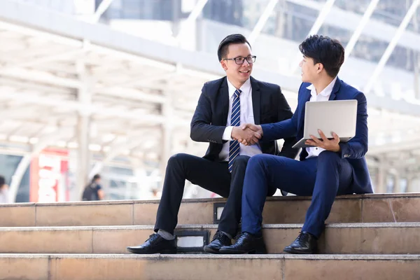 Asyalı iki işadamları oturan şehir içinde laptop üzerinde çalışıyoruz