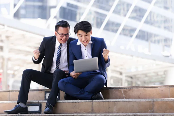 Asyalı iki işadamları oturan şehir içinde laptop üzerinde çalışıyoruz