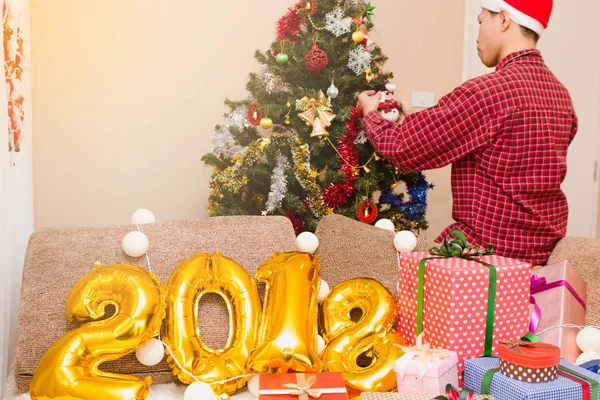 Genç erkekler dekorasyon Noel ağacı hoş geldiniz geliyor tatil için.