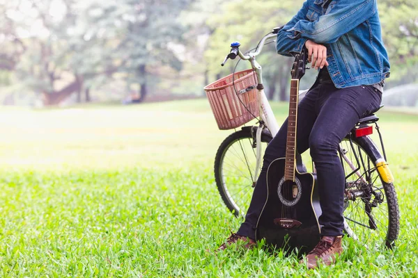 Portrait asian young men sitting on bicycle play guitar