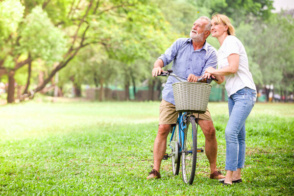 Старшая пара, гуляющая на велосипеде, счастливо разговаривает.
.