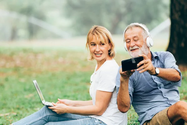 Üst düzey çift çimen parkta otururken müzik keyfini çıkarın