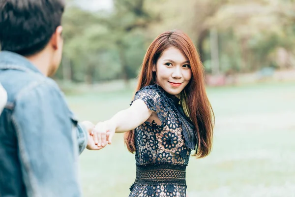 Asya çift aşık bir parkta doğanın büyük bir alanı altında ellerini tutun.