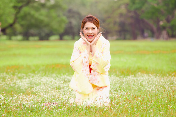 Asian young girl wearing a kimono in natural green grass.
