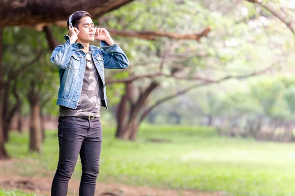 Asya genç erkekler silah doğada ayağa kalk, kulaklık ile müzik dinlemek.