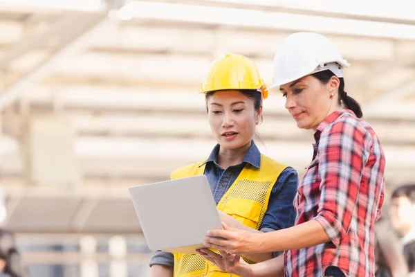 Bina inşaat şehir içinde laptop ile plan üzerinde çalışan iki kadın mühendisler