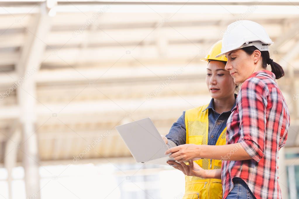 Engineers two woman working on plan building construction with laptop in city