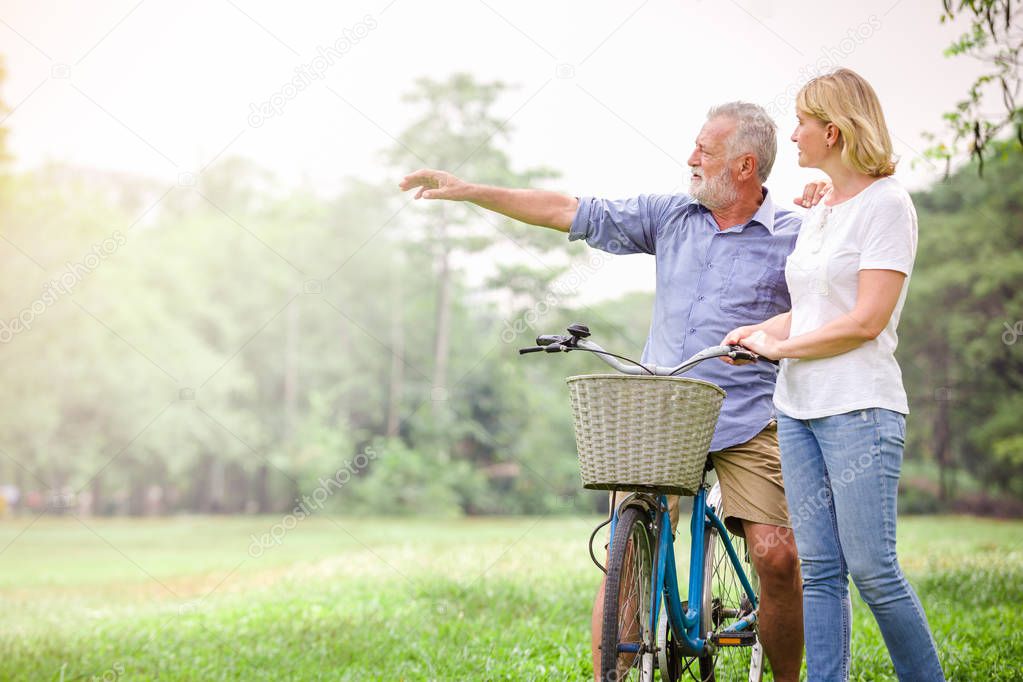 Senior couple walking their bike along happily talking happily.