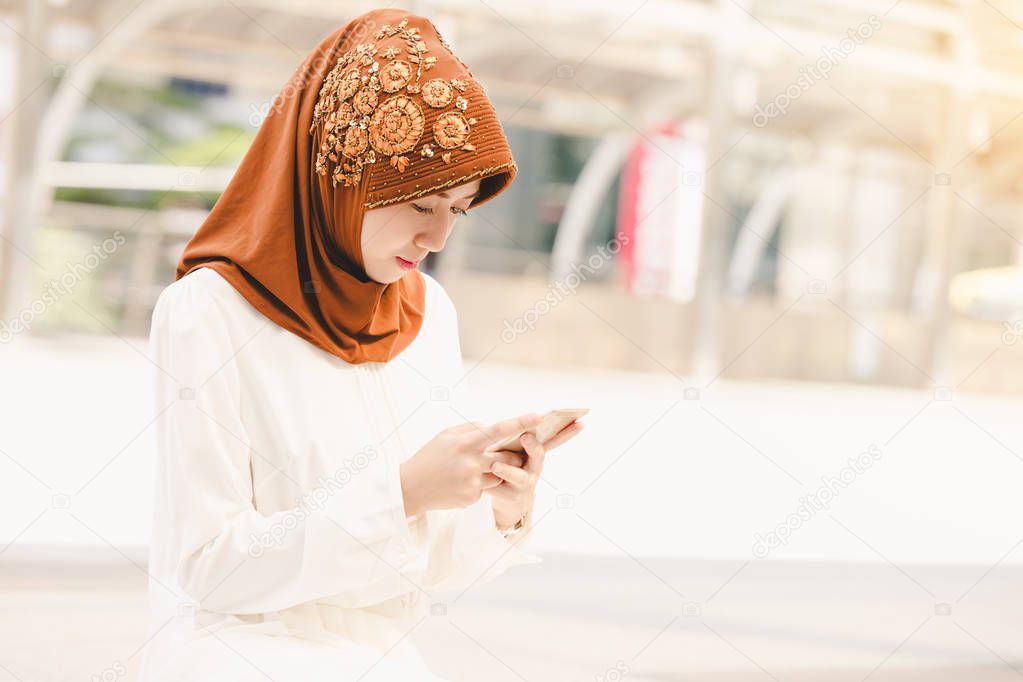 Portrait happy muslim young woman using mobile phone in city