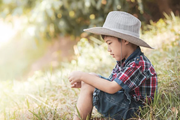 Şirin portre çimenlerin üzerinde oturan Asya küçük çocuk