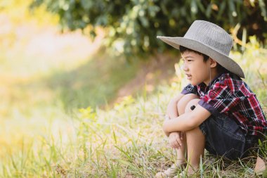 Şirin portre çimenlerin üzerinde oturan Asya küçük çocuk