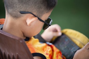 Asyalı küçük çocuk oturan bir akıllı telefon, teknoloji ve insan kavramı ile oyun online oyun