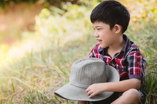Şirin portre çimenlerin üzerinde oturan Asya küçük çocuk