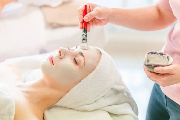 Bela Jovem Spa Aplicando Creme Máscara Cosmética Rosto Relaxante Receber — Fotografia de Stock